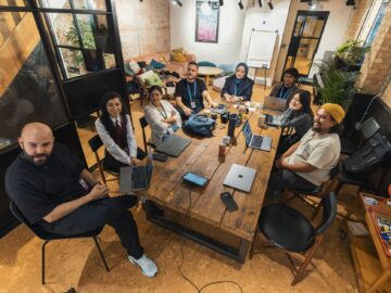 Ondernemer en medewerkers bespreken samen AI-geletterdheid voor ondernemers aan een tafel op kantoor