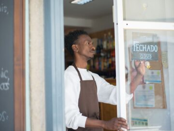 Ondernemer beantwoordt klantvragen op een laptop in een kleine winkel, ondersteund door AI klantenservice