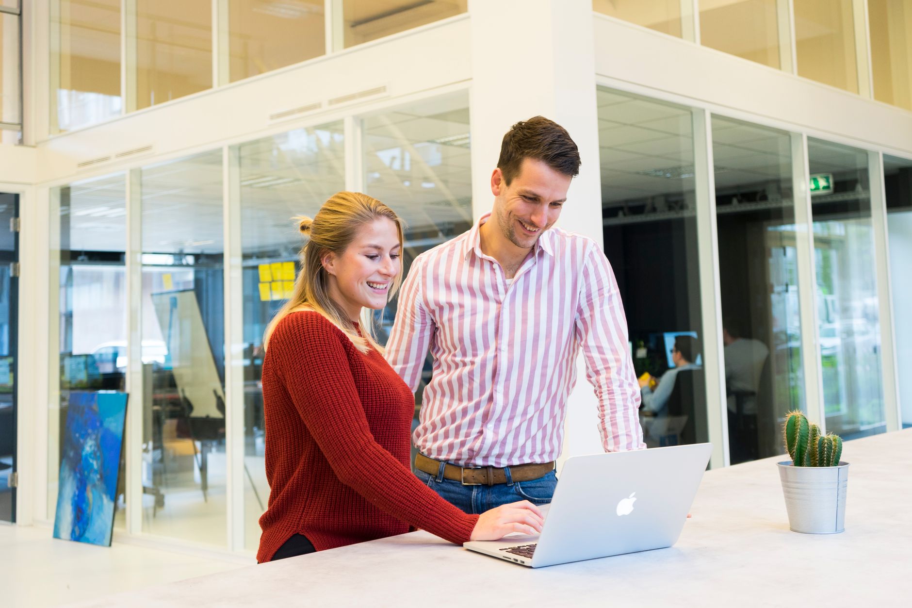 Collega's werken samen aan een laptop op kantoor