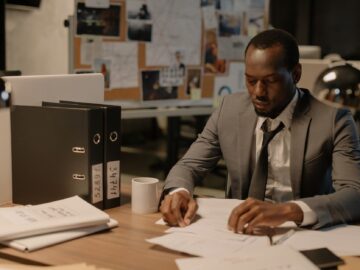 Medewerker op kantoor ordent documenten op een laptop met hulp van Copilot in SharePoint