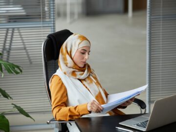 Werknemer aan een bureau leest documenten op een laptop en gebruikt NotebookLM om samenvattingen te maken