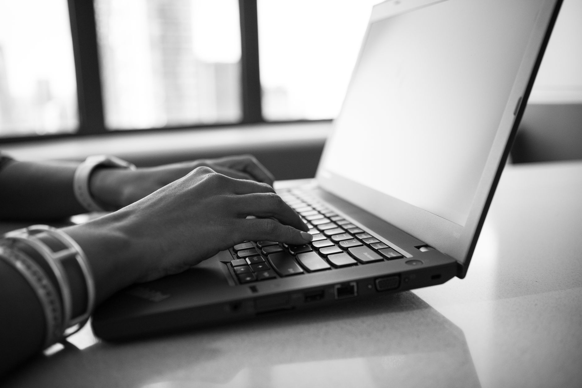 Iemand typt op een laptop aan een bureau op kantoor